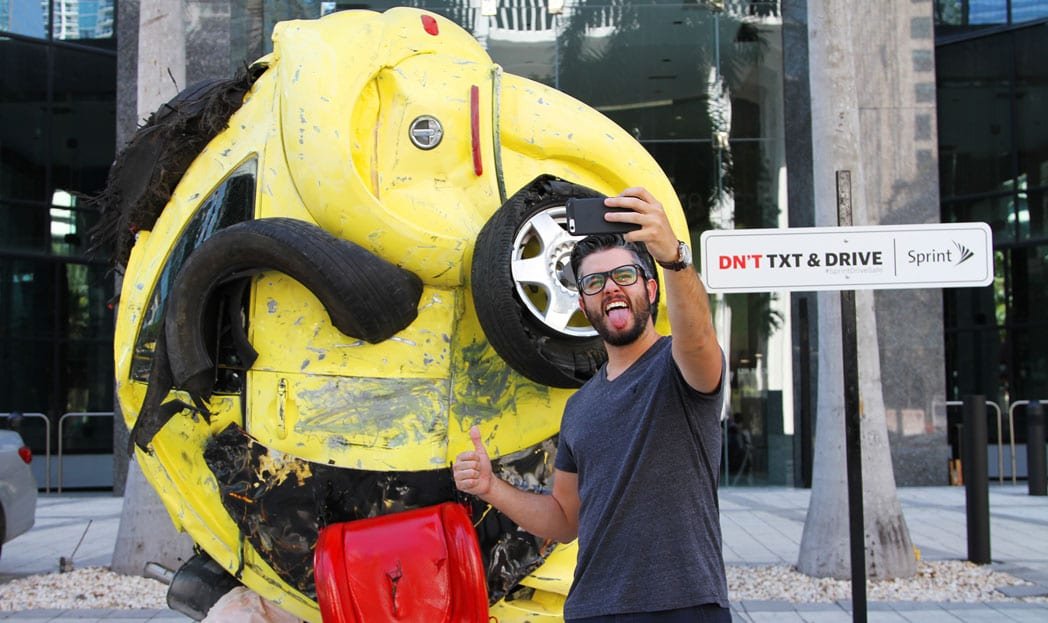 Escultura de emoji feita com um carro batido alerta sobre enviar SMS dirigindo